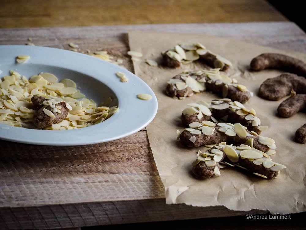 Vor dem Backen werden die veganen Mandelhönchen in Mandeln gewälzt.