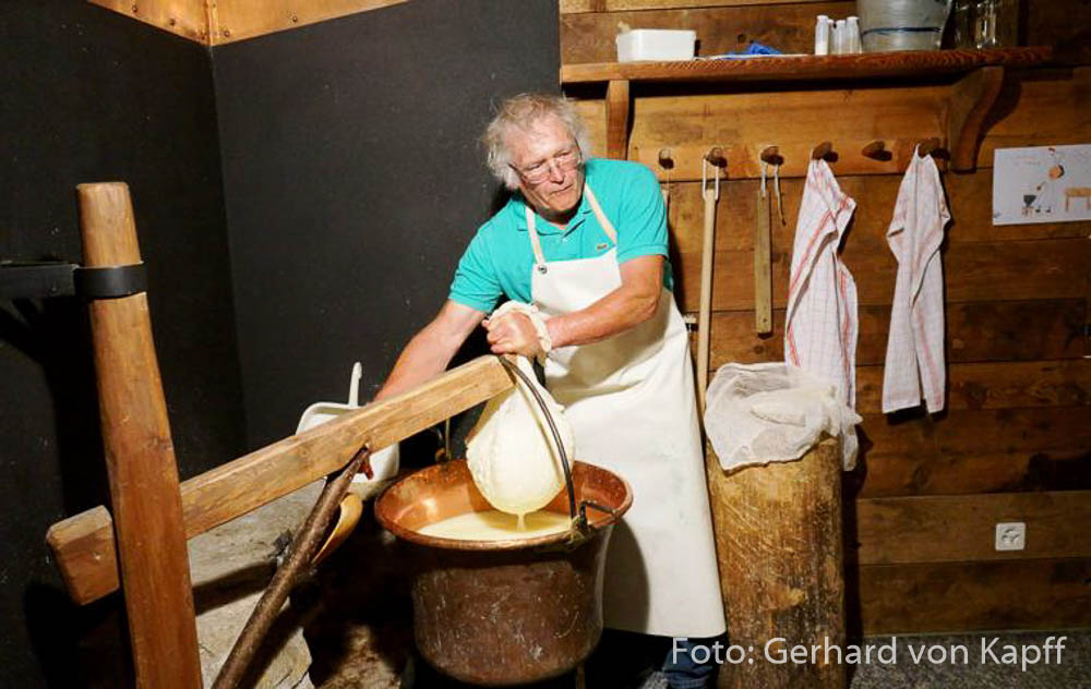 Käseproduktion, Airolo, Schaukäserei St. Gotthard, Käse wird in einem Tuch aus dem Kupferkessel geschöpft